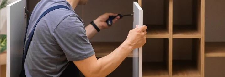 Person baut Schrank zusammen